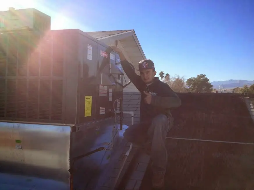 HVAC technician performing Air Duct Repair on a rooftop unit in Flowood